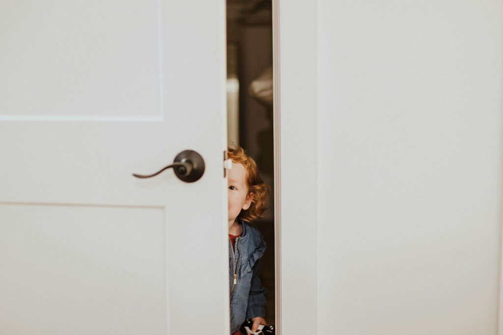 Petite fille anxieuse qui se cache derrière la porte